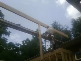 Carpenter setting a ridge beam over a new addition frame — Ice Dam Removal by Roofing Brothers in Eggleston