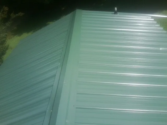 New green metal panels meeting at the ridge of a roof — Flat Roof Repair work by our crew in Eggleston