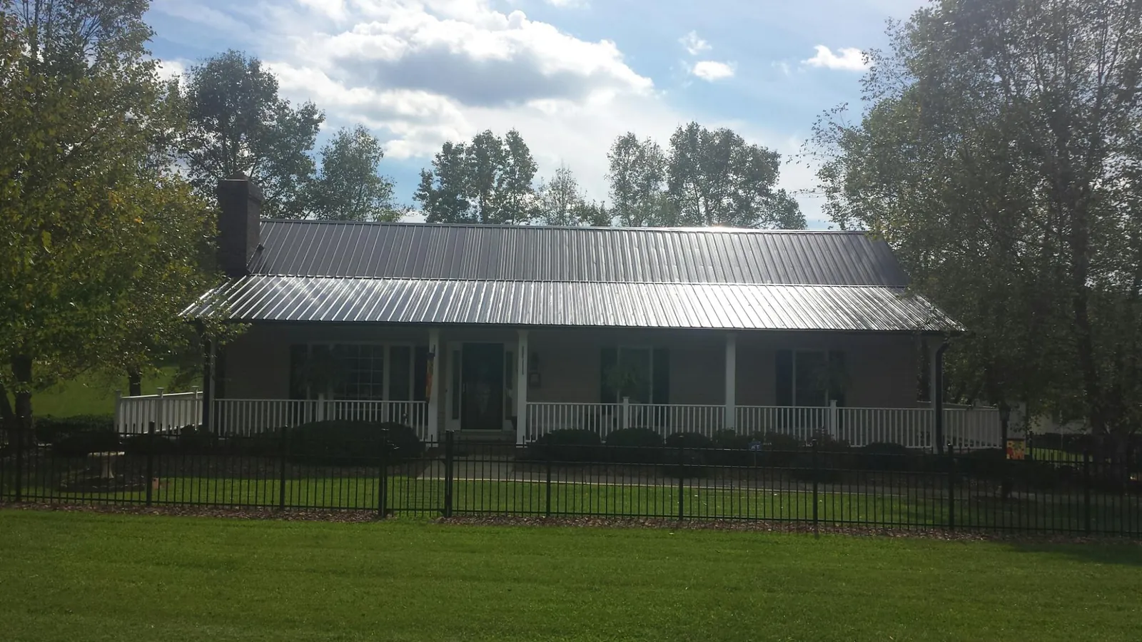 Gray metal roof on a brick ranch with a full width front porch — Gutter Guard Installation work by our crew in Eggleston