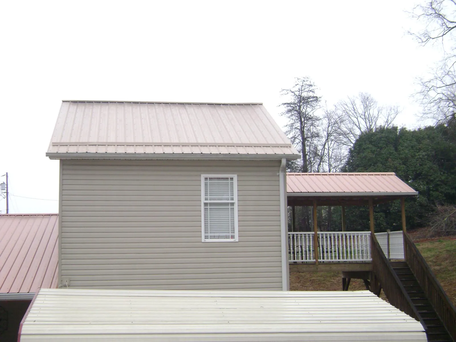 Tan metal roofs on a two story addition and attached porch, from a Roof Replacement job in Eggleston