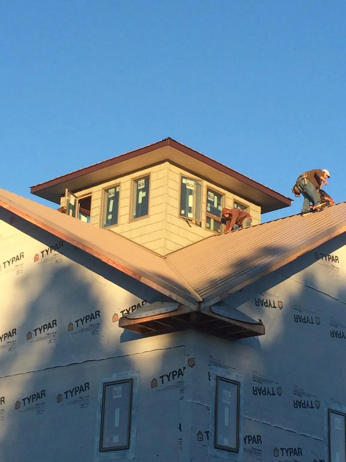 Roofers working around a rooftop cupola on a new metal roof at sunset — Roof Waterproofing in Eggleston by Roofing Brothers